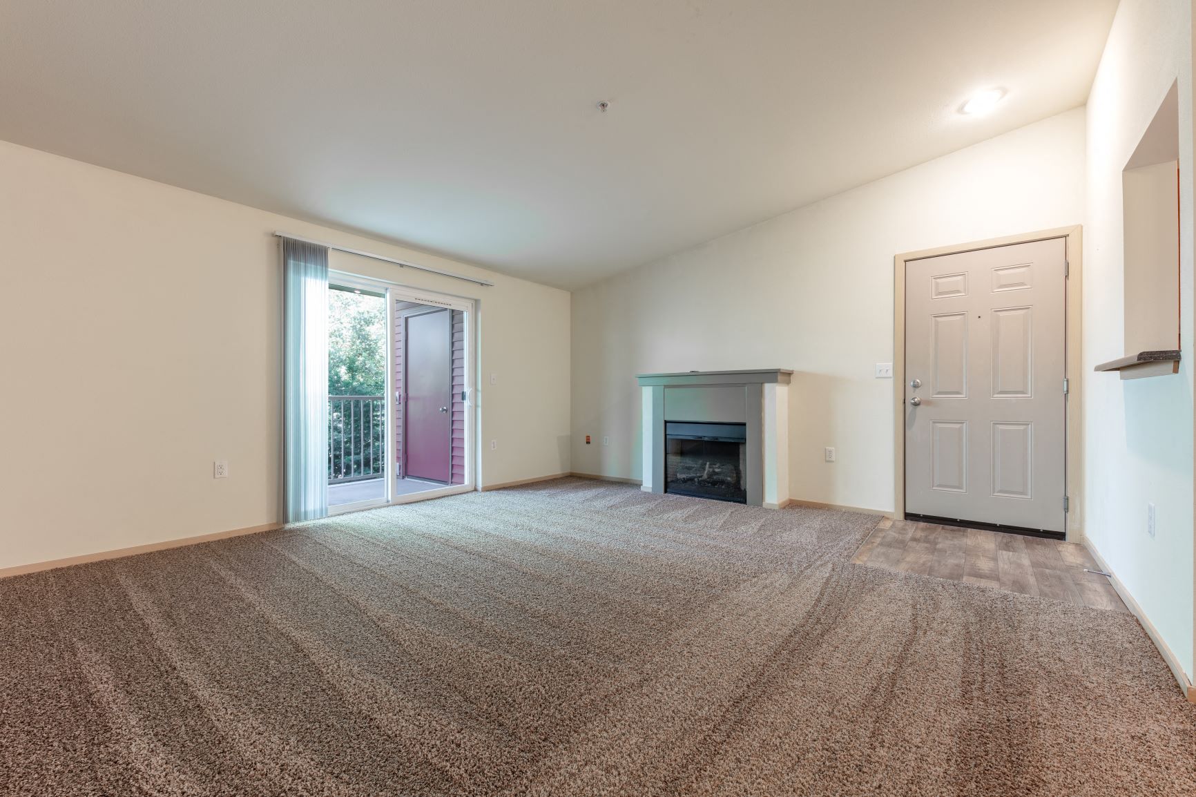 an empty living room with a fireplace and a door