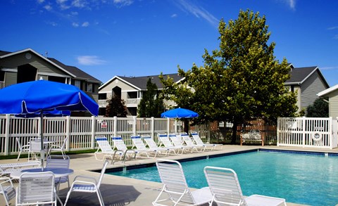 a swimming pool with chairs and umbrellas in front of houses