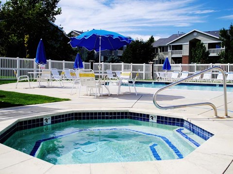 a swimming pool with chairs and umbrellas next to a house
