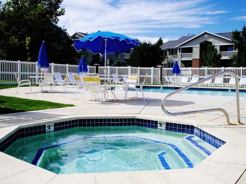 a hot tub and patio with chairs and umbrellas
