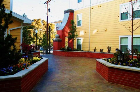 a courtyard with brick walls and plants in front of a building