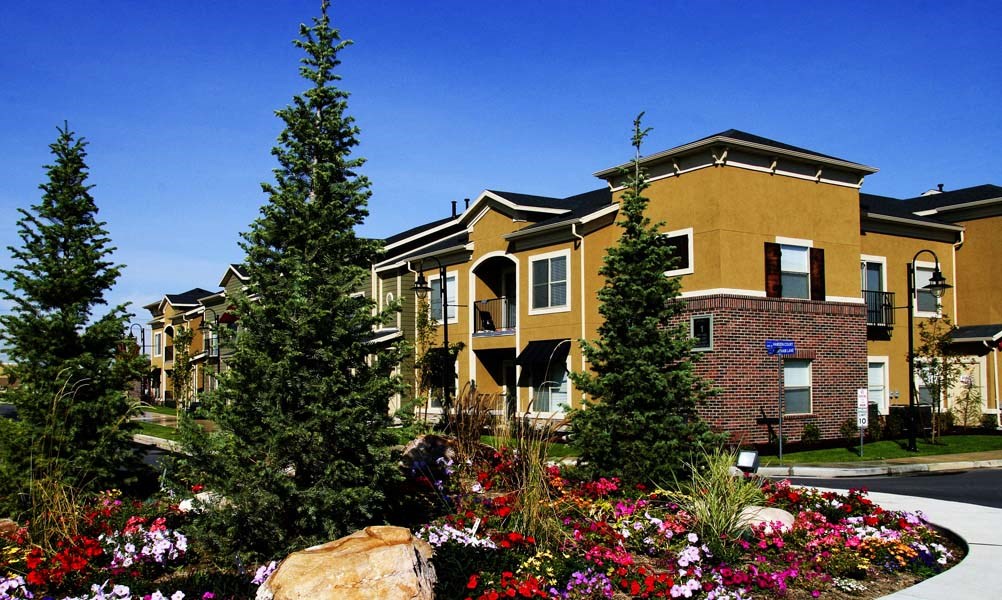 an apartment building with trees and flowers in front of it