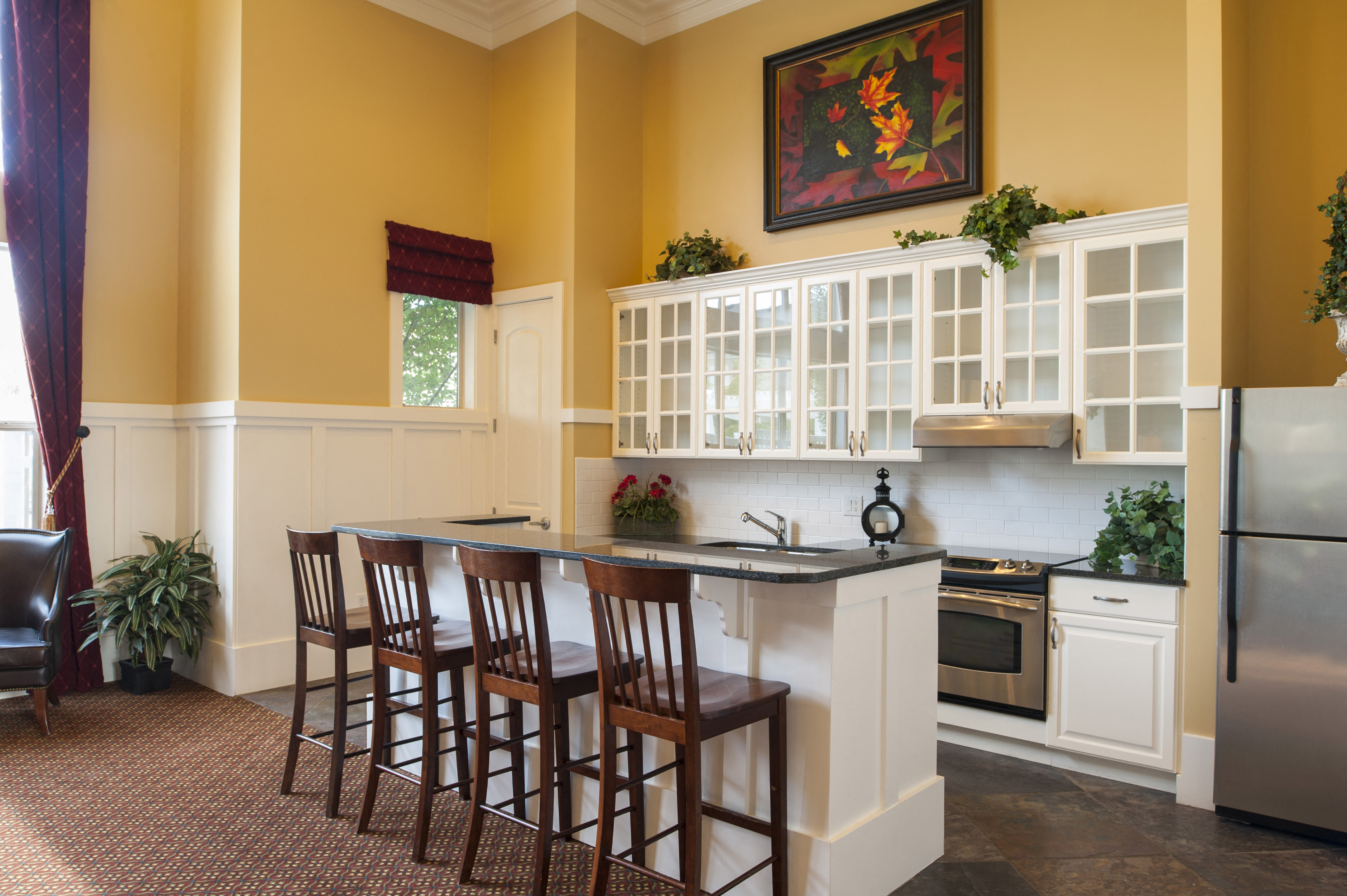 a kitchen with yellow walls and a counter with chairs