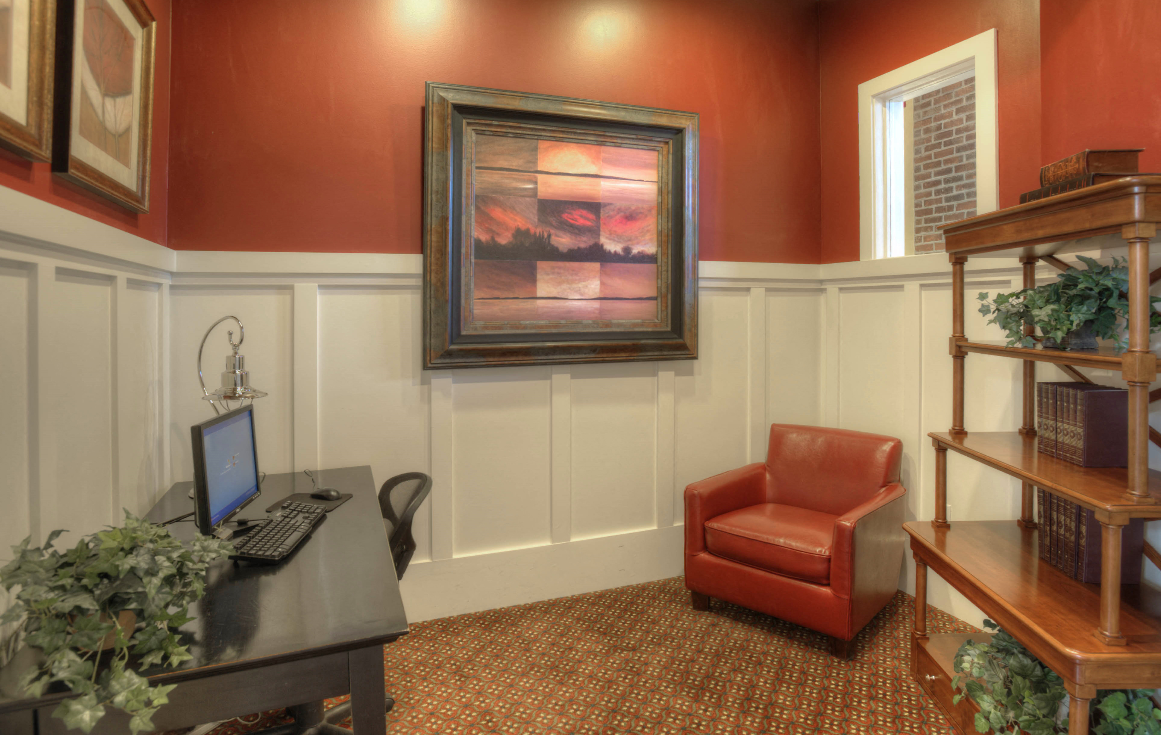 a home office with a computer and a red chair