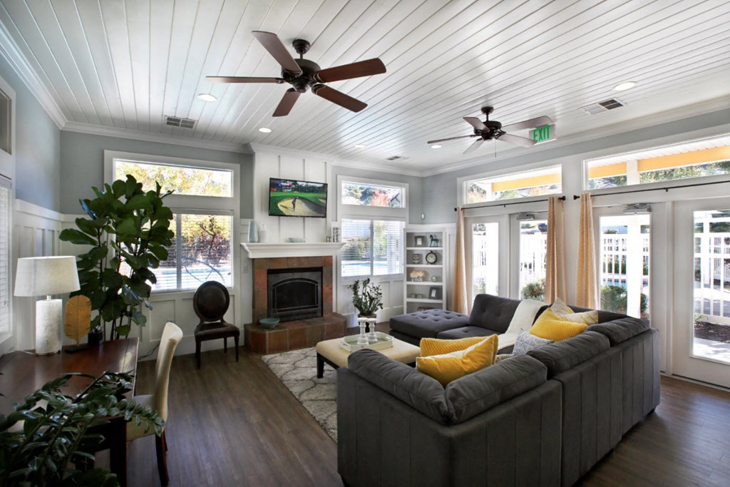 Liberty Hill Apartments, Draper, Utah, common area clubhouse with a grey couch, ceiling fan, television and fireplace.