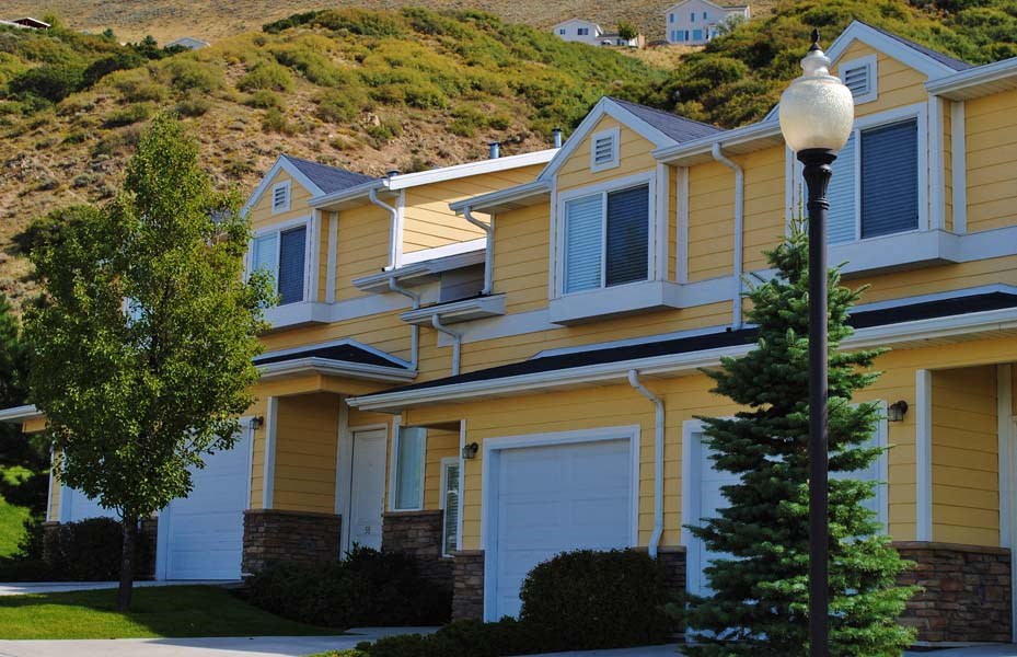 Liberty Hill Apartments, Draper, Utah, yellow townhome with a white garage door and a tree in front.