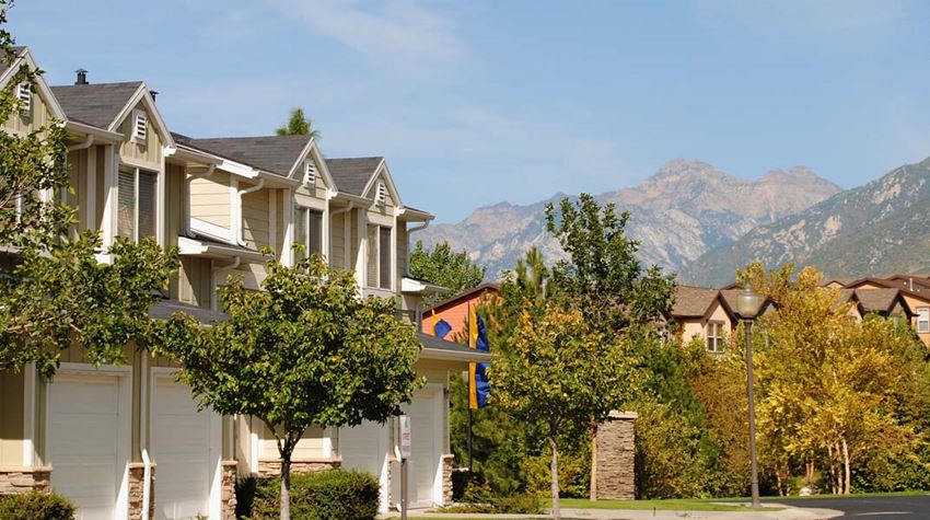 a row of houses with trees and mountains in the background