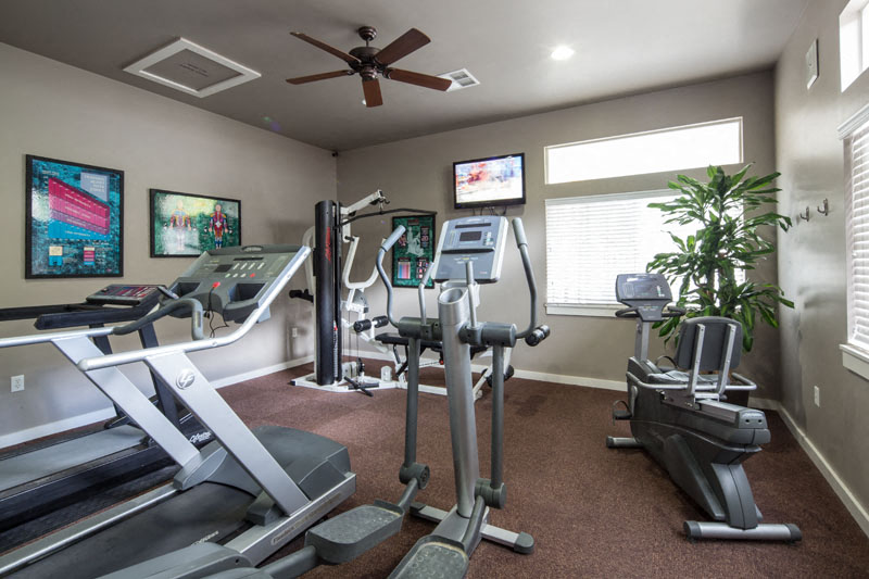 treadmills and other exercise equipment in the gym of a home