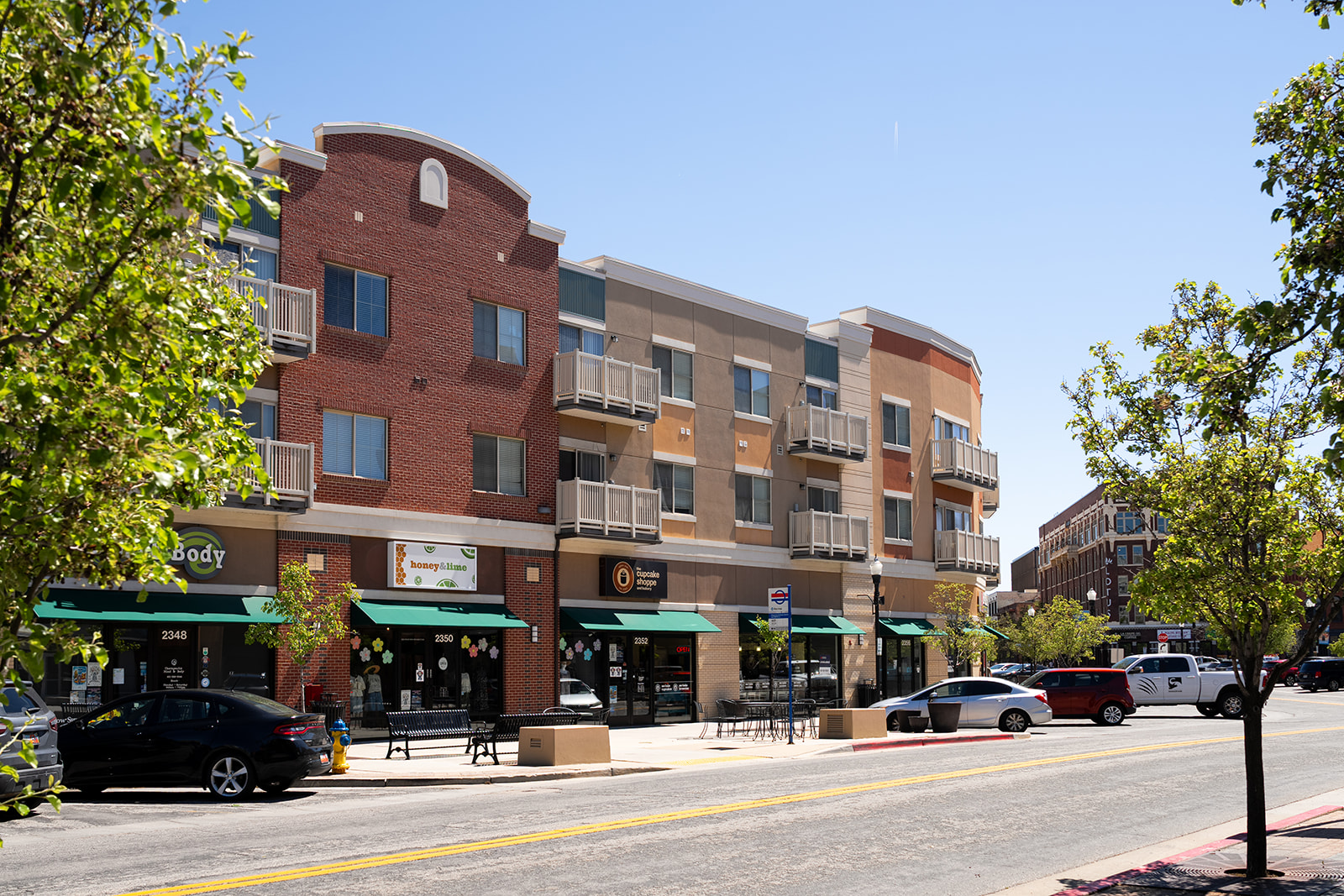 A street view of a building with a green awning and a tree in front of it.