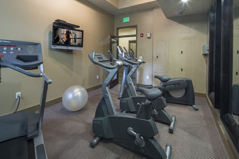 a gym with exercise machines and a tv on the wall