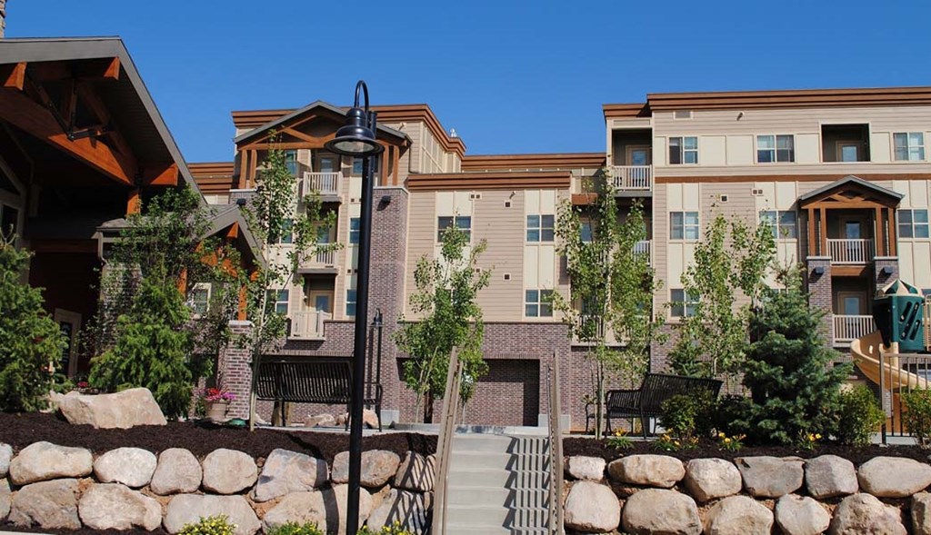 an apartment building with trees and a stone wall