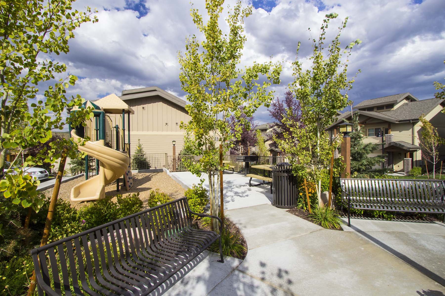 a playground in a yard with benches and trees