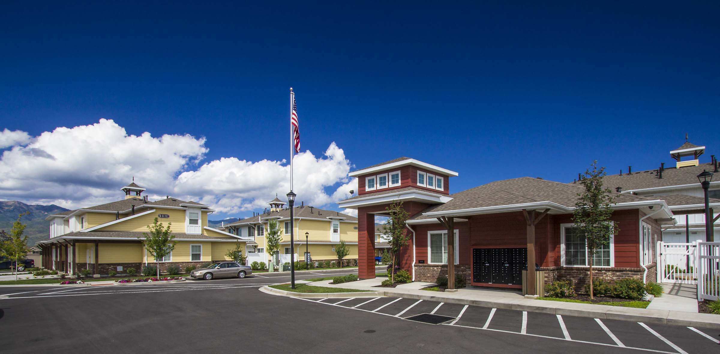 the front of a building with an flag and a parking lot