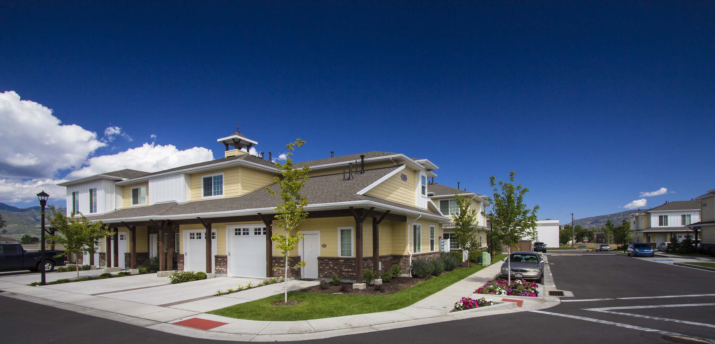 the front of a house with a street and cars parked in front
