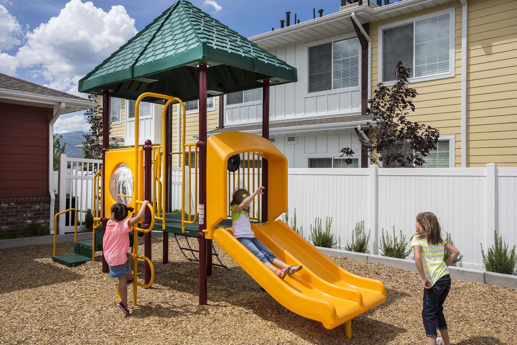 three children playing on a playground at a home