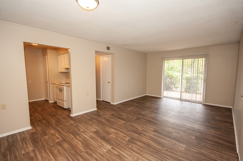 an empty living room and kitchen with wood flooring