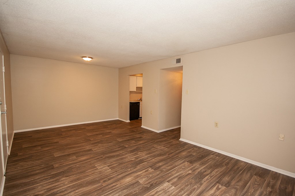 an empty living room with wood flooring and white walls