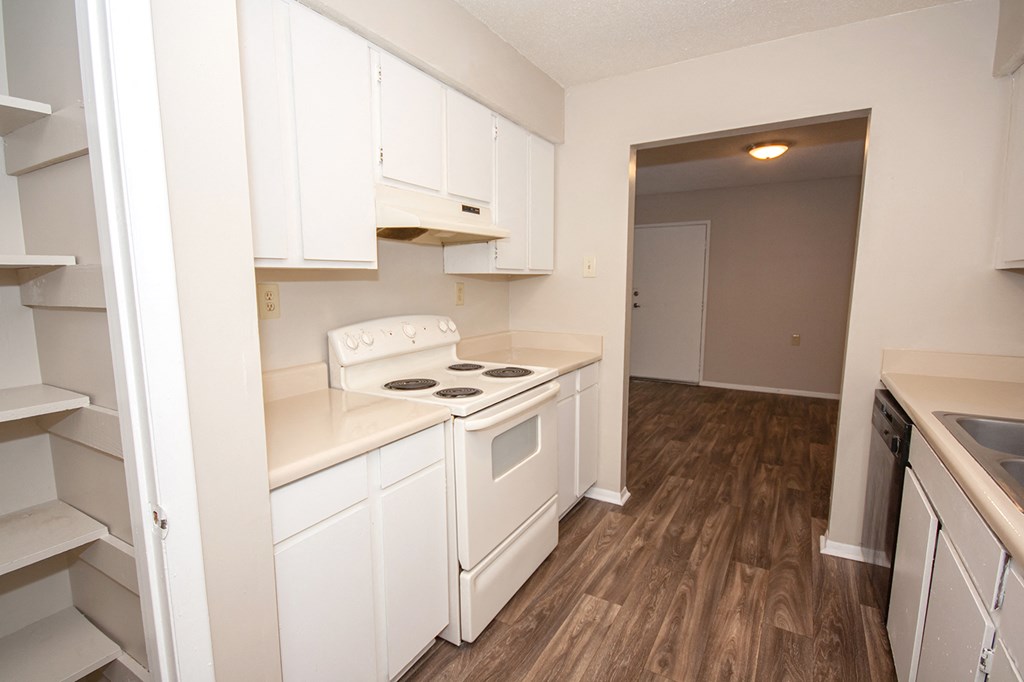 an empty kitchen with white cabinets and a white stove
