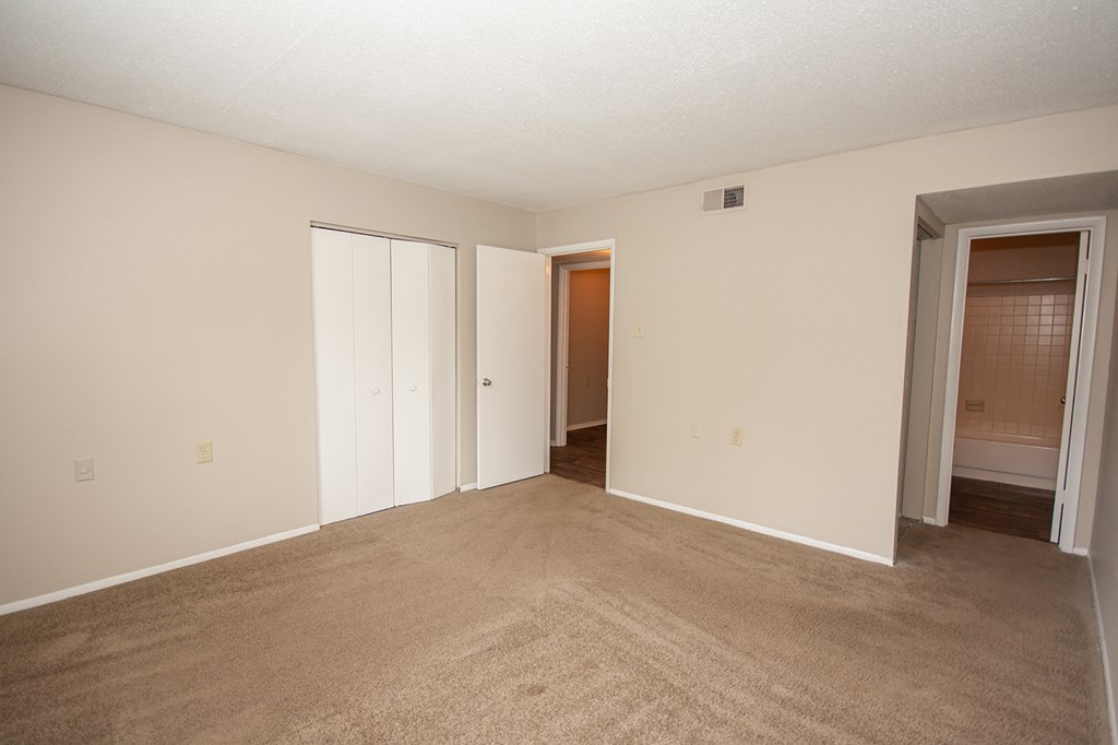 an empty living room with carpet and a door to a closet