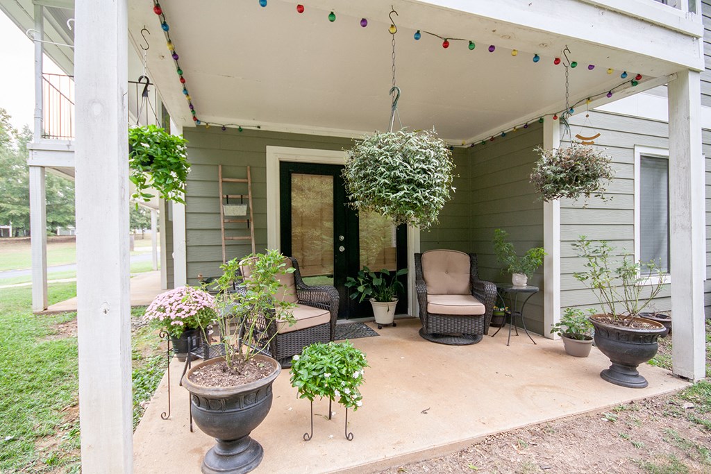 a porch with potted plants and chairs on it
