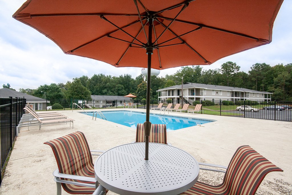 our apartments have a large pool and patio with chairs and an umbrella