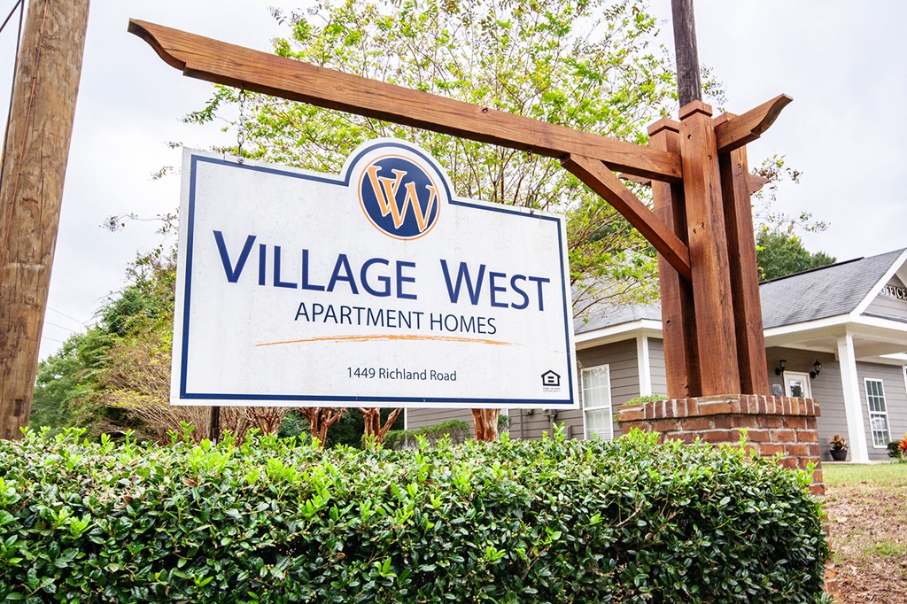 a village west apartment homes sign in front of a house