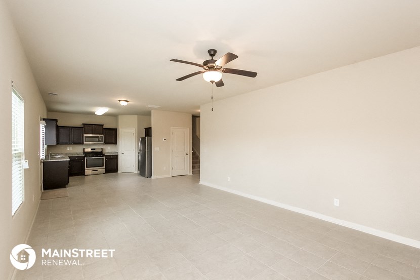 an empty living room and kitchen with a ceiling fan