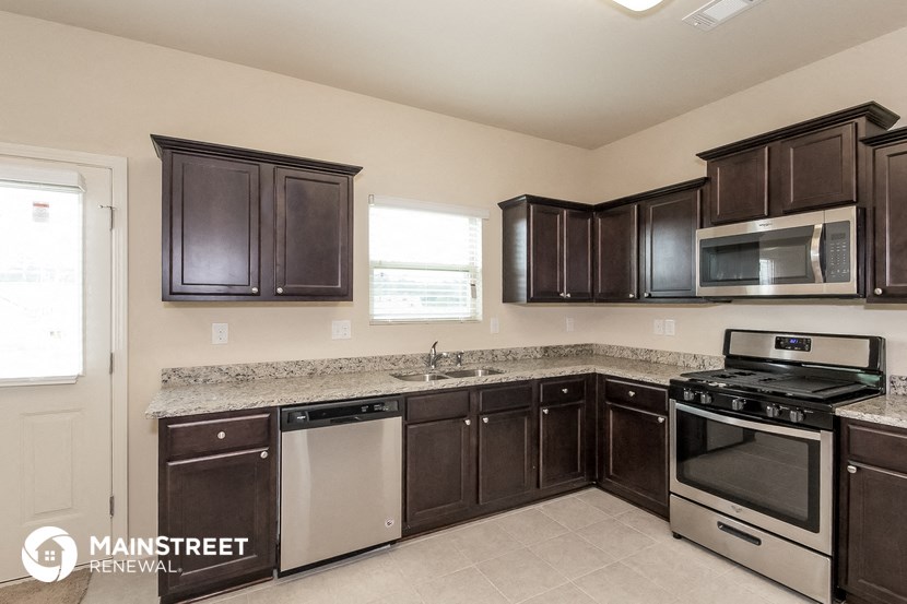 a kitchen with dark wood cabinets and granite counter tops and stainless steel appliances