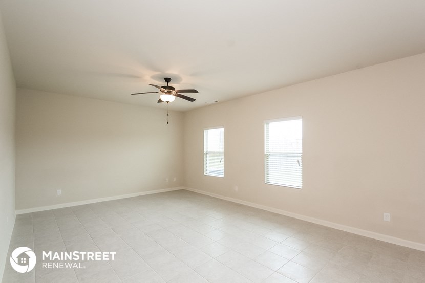 the spacious living room with ceiling fan and tiled floors