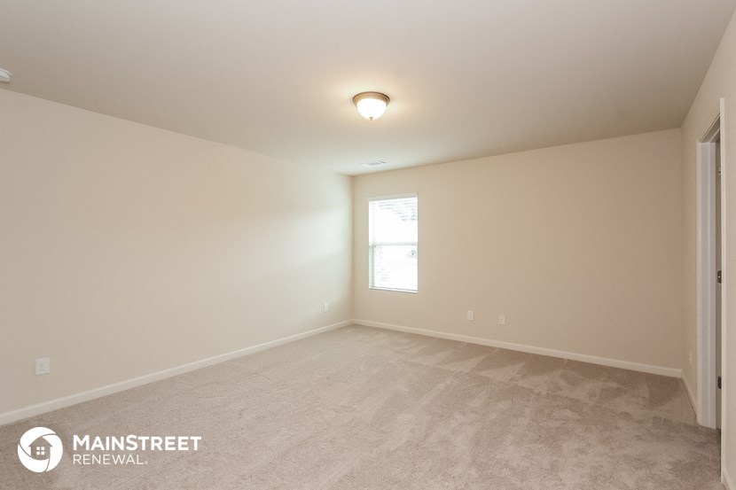 the spacious living room with carpeting and a window
