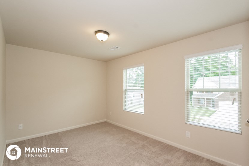the spacious living room with two windows and beige carpeting