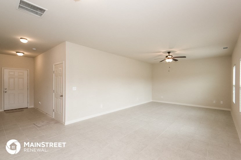 the living room of an empty house with a ceiling fan