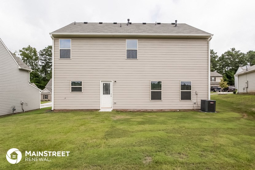 the back of a white house with a grassy yard