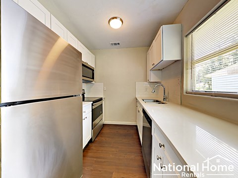 A kitchen with a refrigerator, microwave, and a sink.