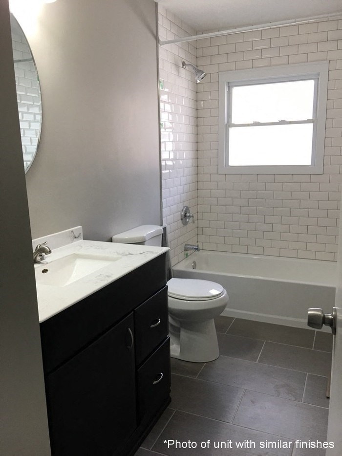 A bathroom with a white sink, toilet, and tub.