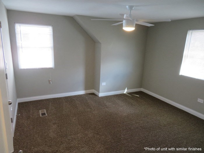 A room with a ceiling fan and carpeted floor.