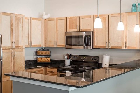 A kitchen with wooden cabinets and a black countertop.