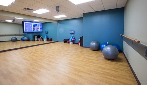A gym with exercise balls and a TV screen.