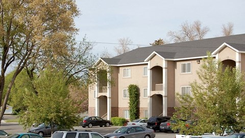 an apartment building with cars parked in a parking lot