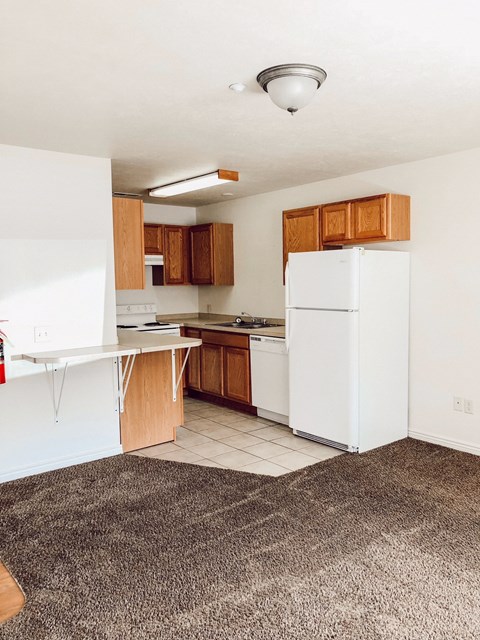 an empty kitchen with white appliances and wooden cabinets