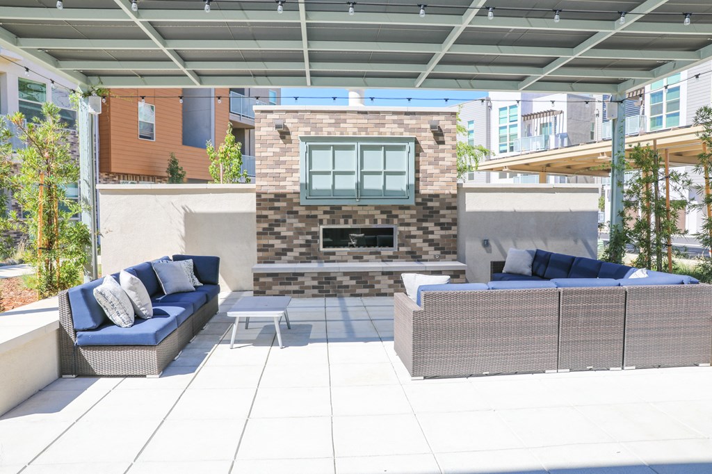 a patio with blue furniture and a brick fireplace
