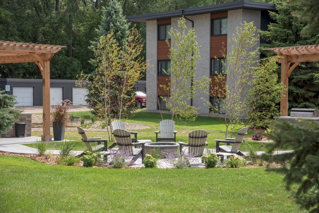 a patio with chairs and trees in front of a building