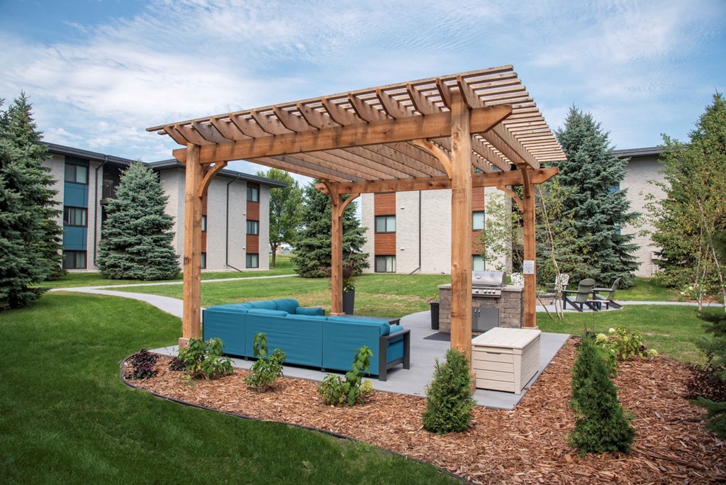 a patio with a blue couch under a wooden pergola