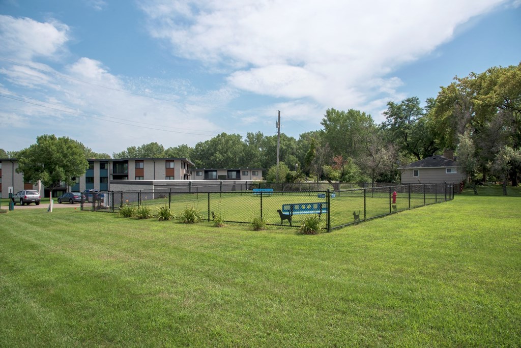 a park with a fence and a bench in front of a building