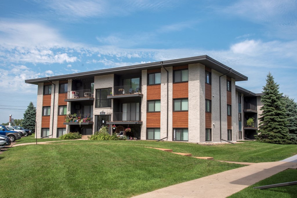 a large apartment building with balconies and a lawn