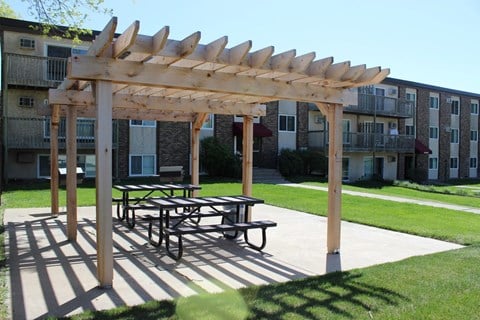 a picnic area with a pergola in front of an apartment building