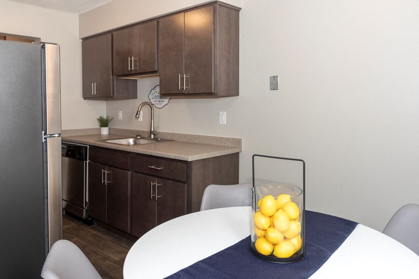 a kitchen with dark wood cabinets and a white table with a vase of lemons on