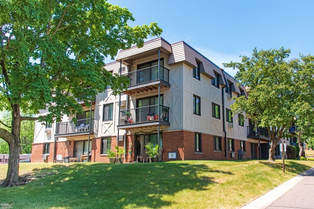 an apartment building with a lawn and trees