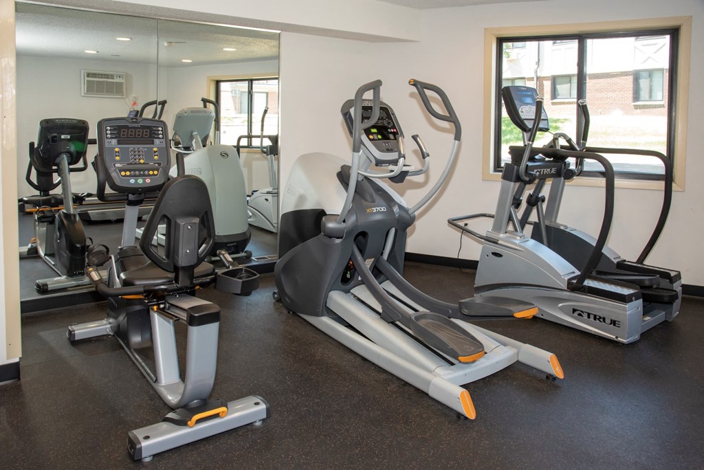 a gym with cardio equipment on the floor and a mirrored wall