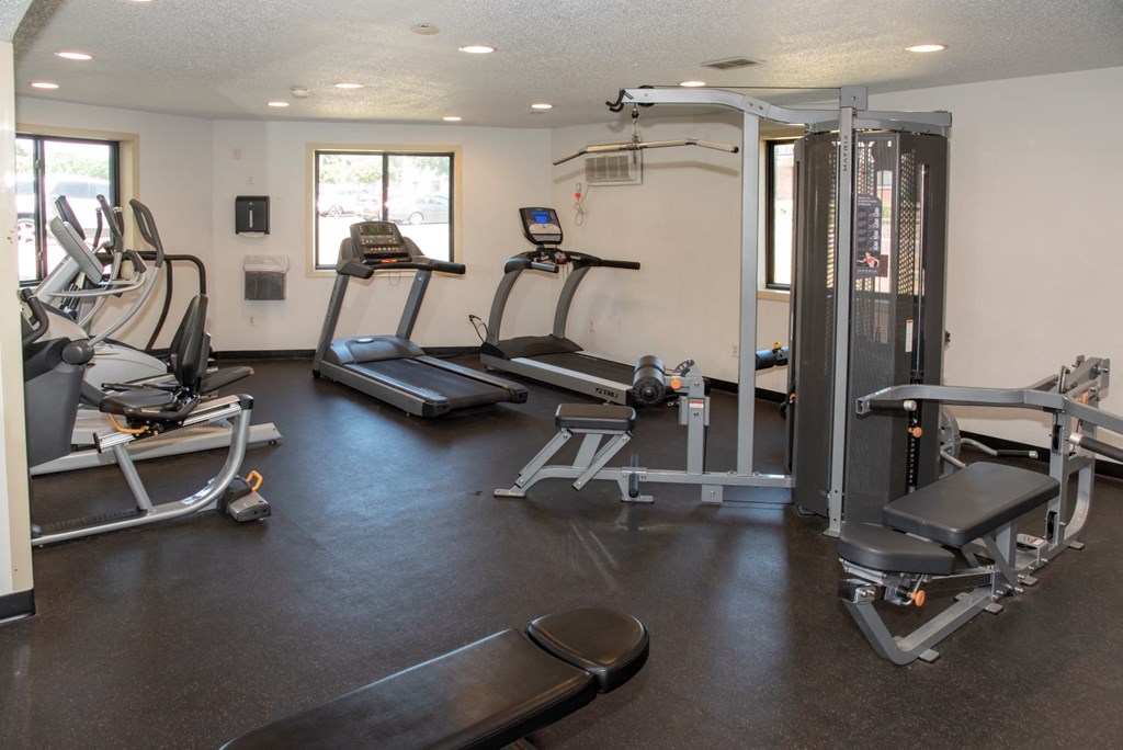 a gym with cardio equipment and weights on the floor